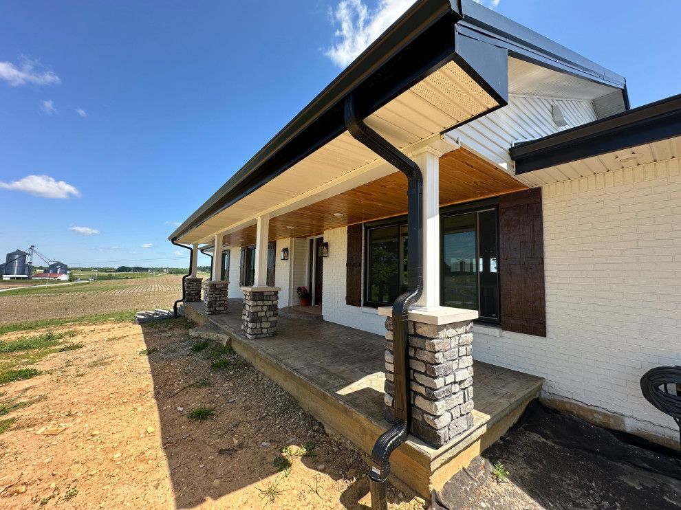 A white house with a large porch and a black gutter.