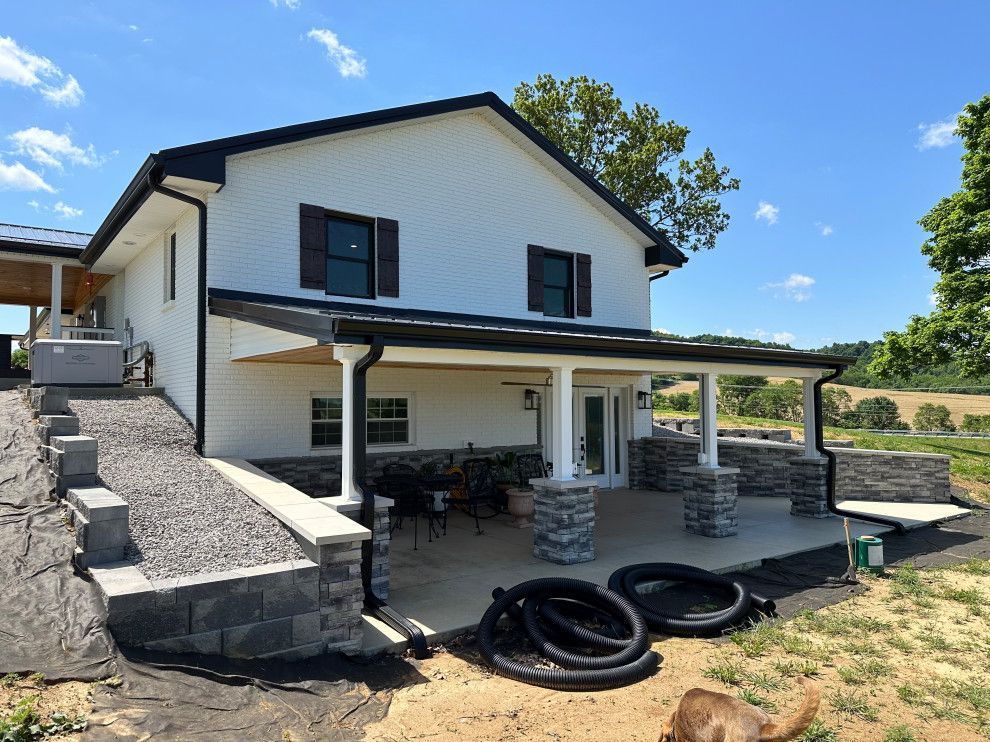 A white house with a porch and a dog in front of it.
