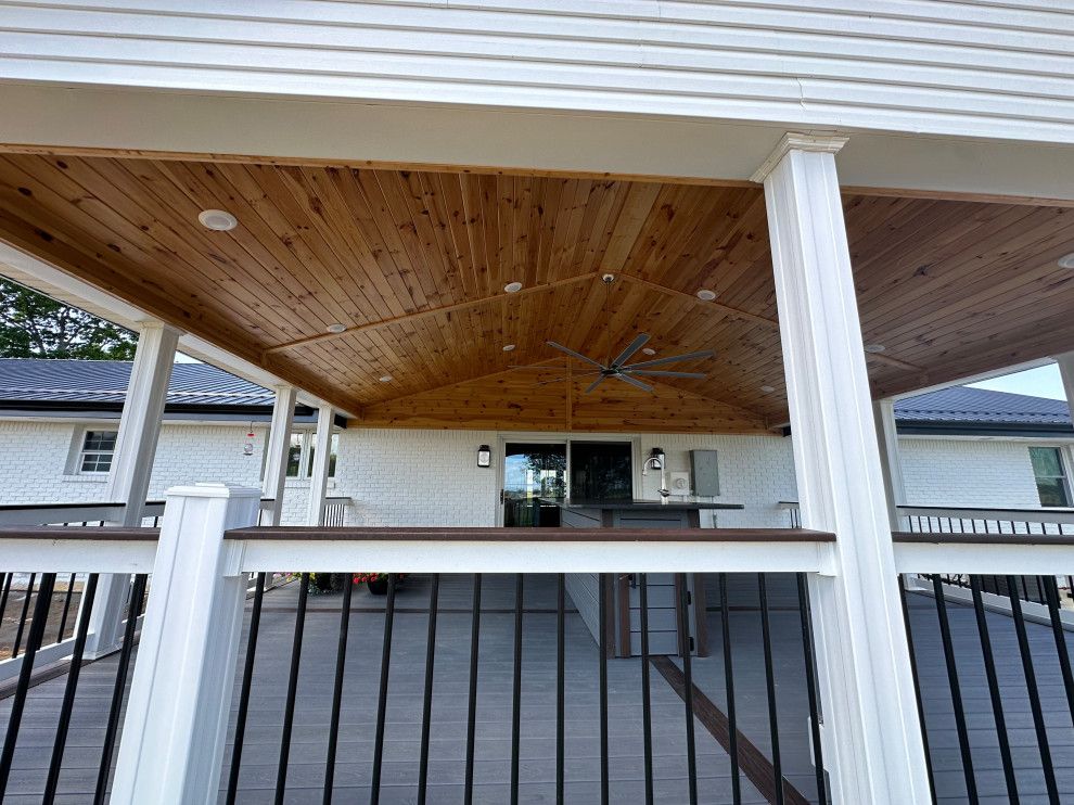 A large deck with a wooden ceiling and a ceiling fan.
