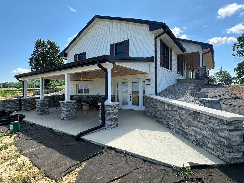A large white house with a large porch and a stone wall.