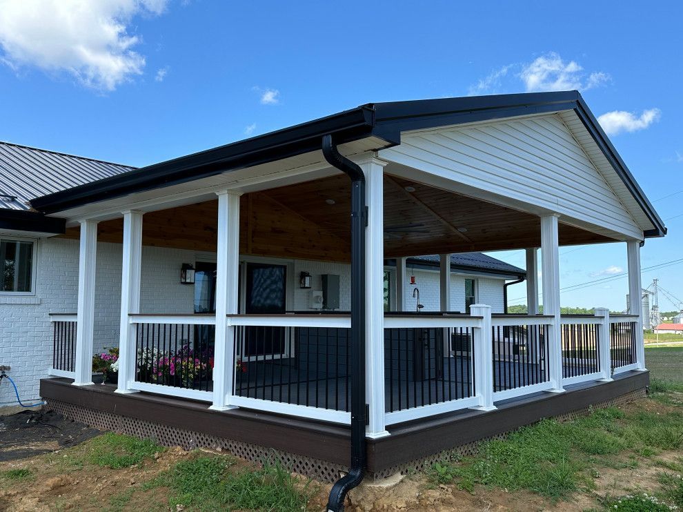 A white house with a porch and a black roof.