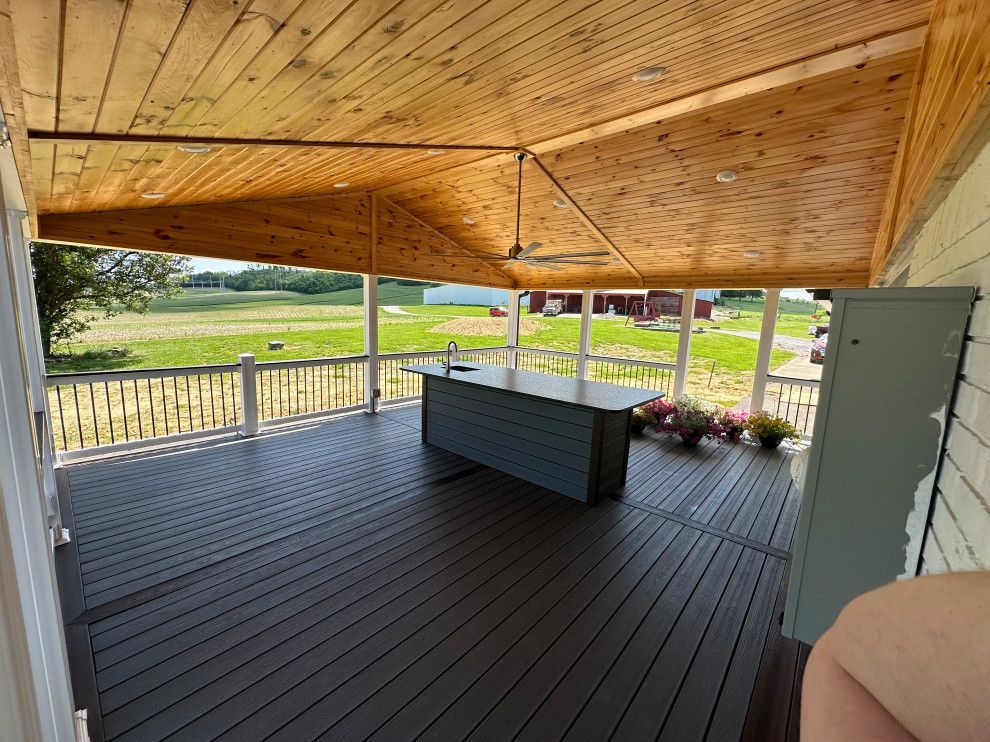 A large porch with a table and a ceiling fan.