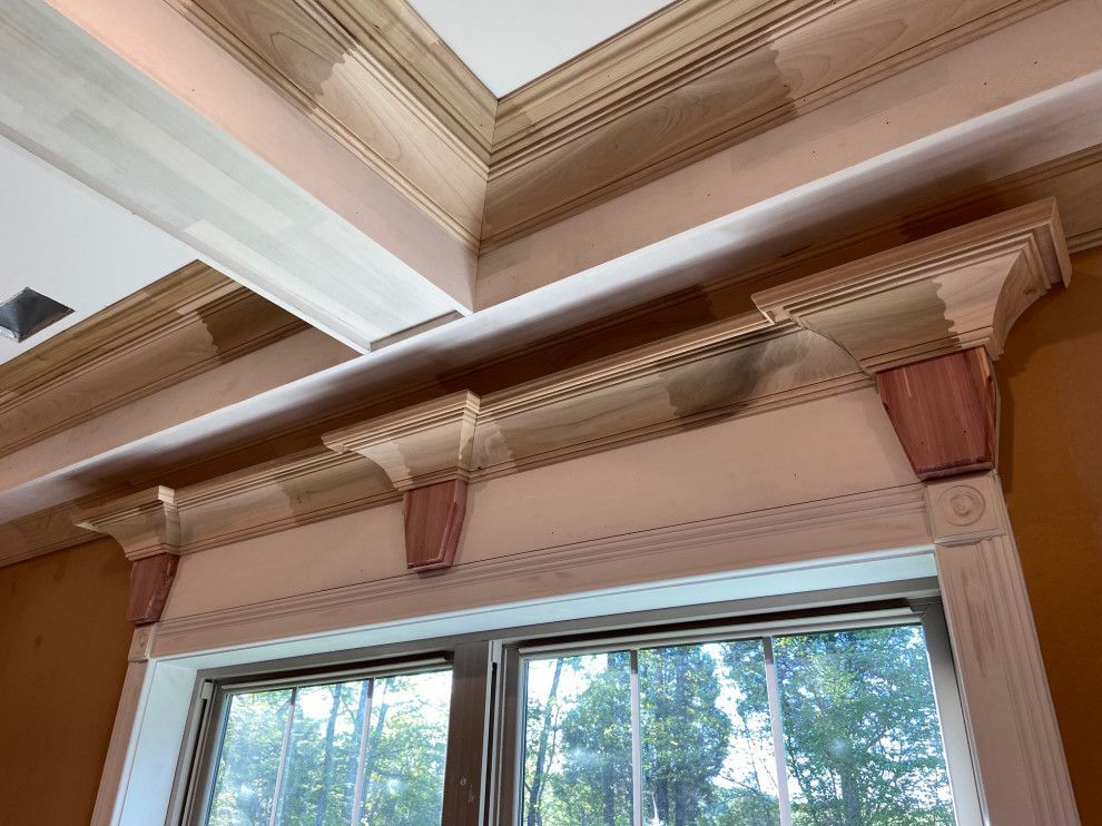 A window in a room with a wooden molding on the ceiling.