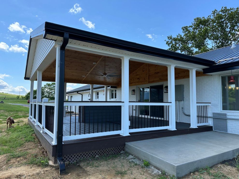 A white house with a large porch and a black railing.