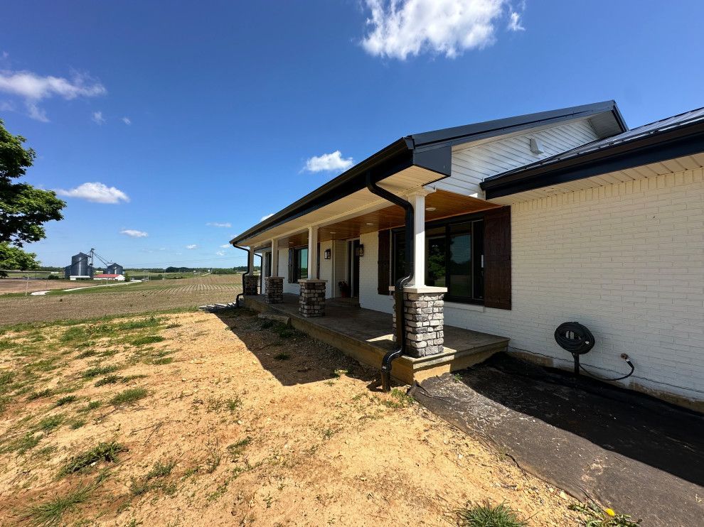 A white house with a porch and a fan on the side of it.