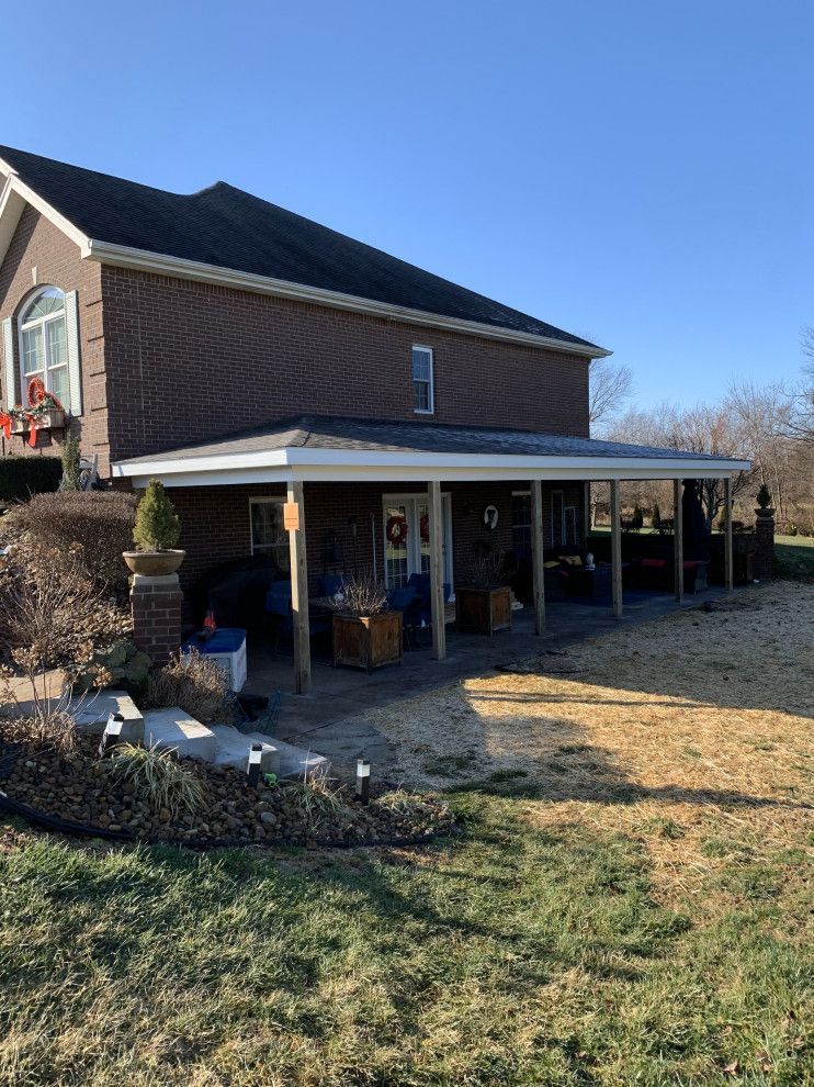 A large brick house with a porch and stairs in front of it.