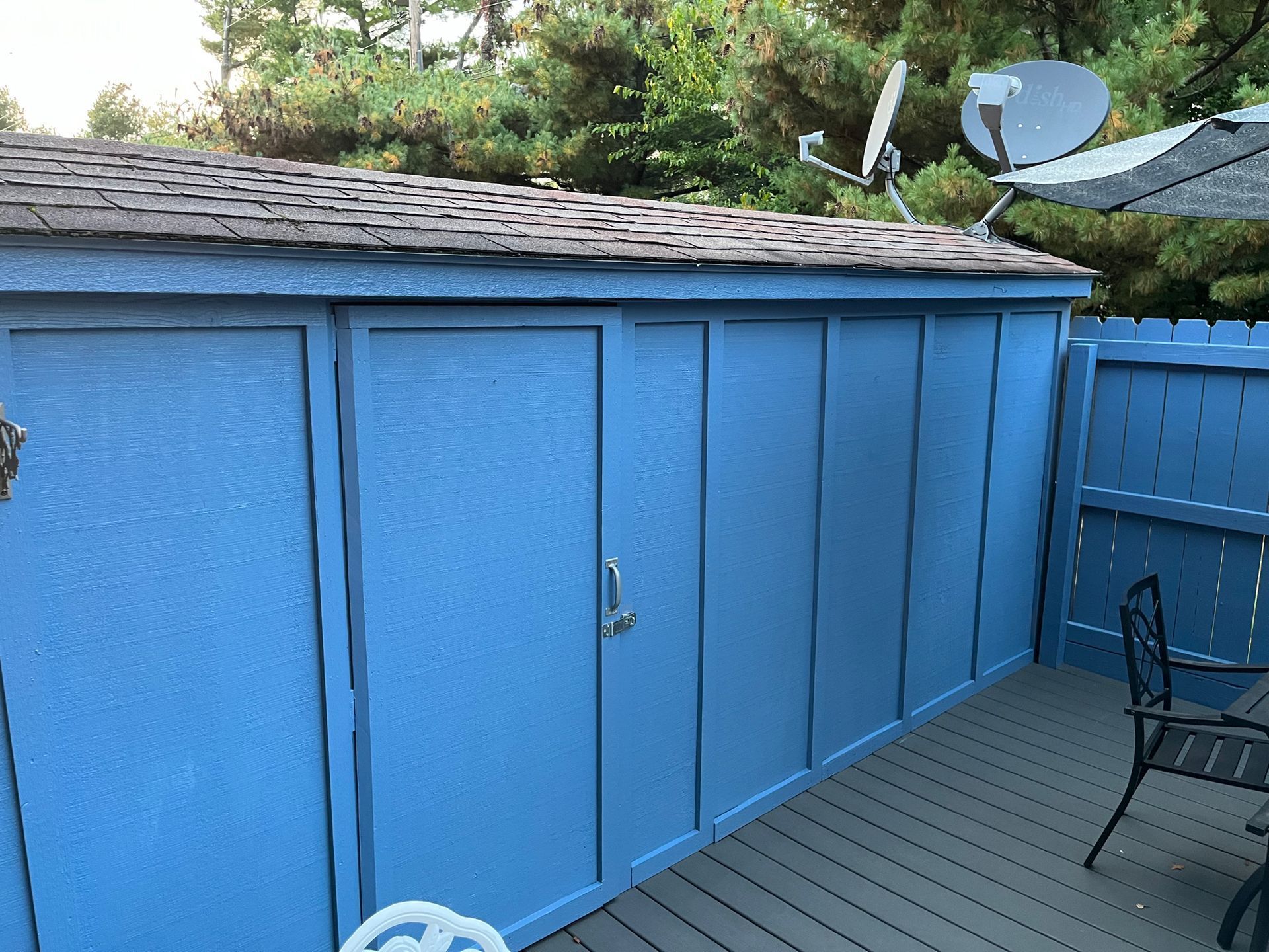 A blue shed with a satellite dish on top of it