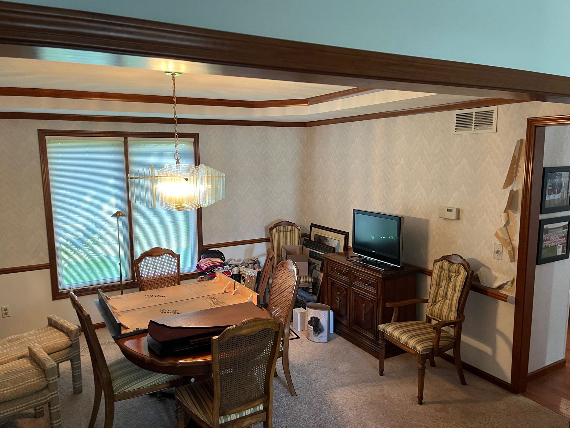 A dining room with a table and chairs and a television.