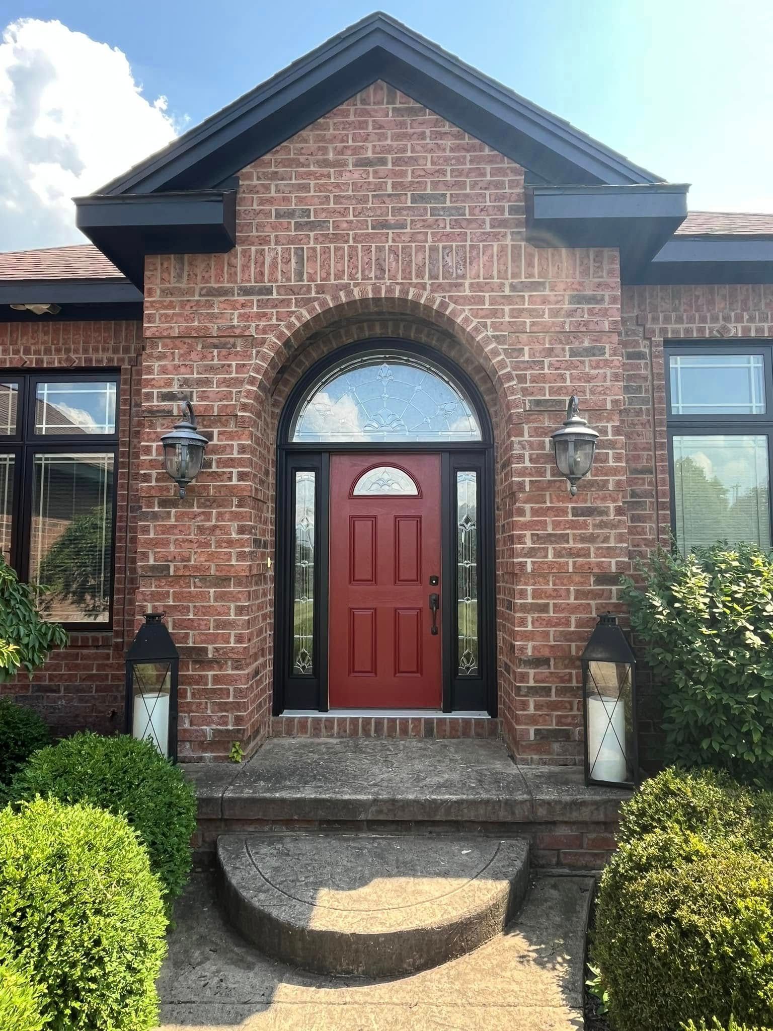A brick house with a red door and black windows
