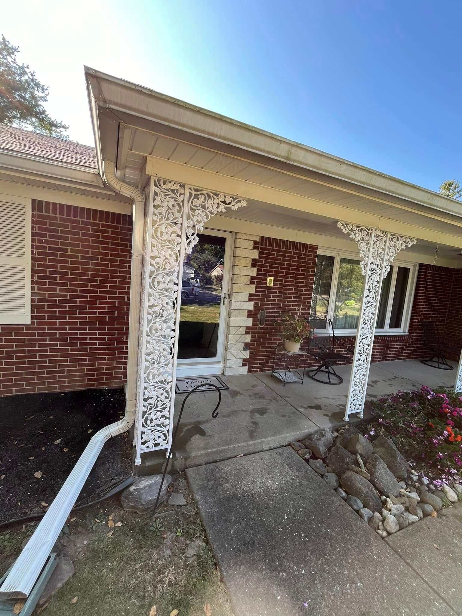 A brick house with a porch and a gutter on the side of it.