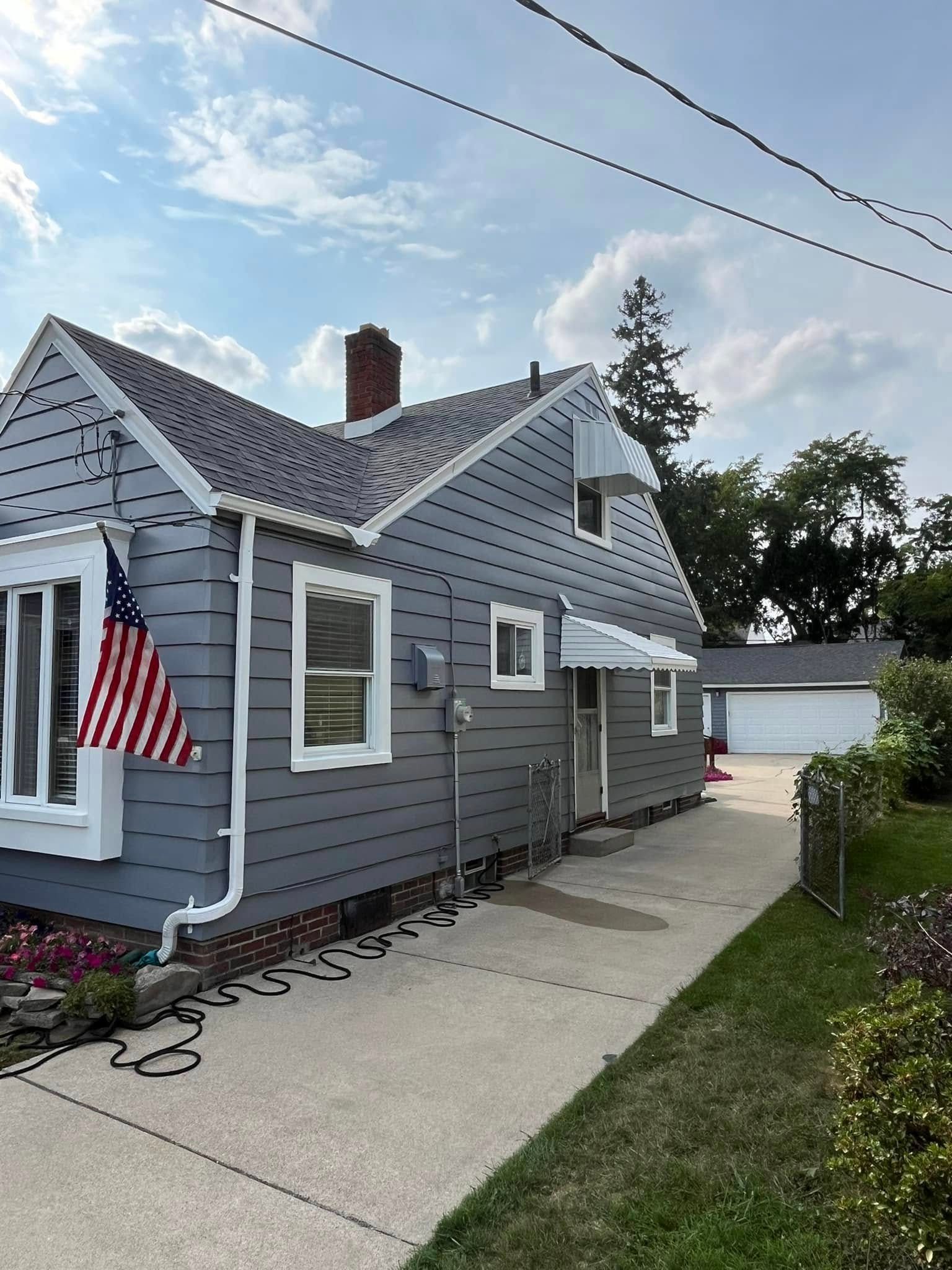 A gray house with an american flag hanging from the side of it.