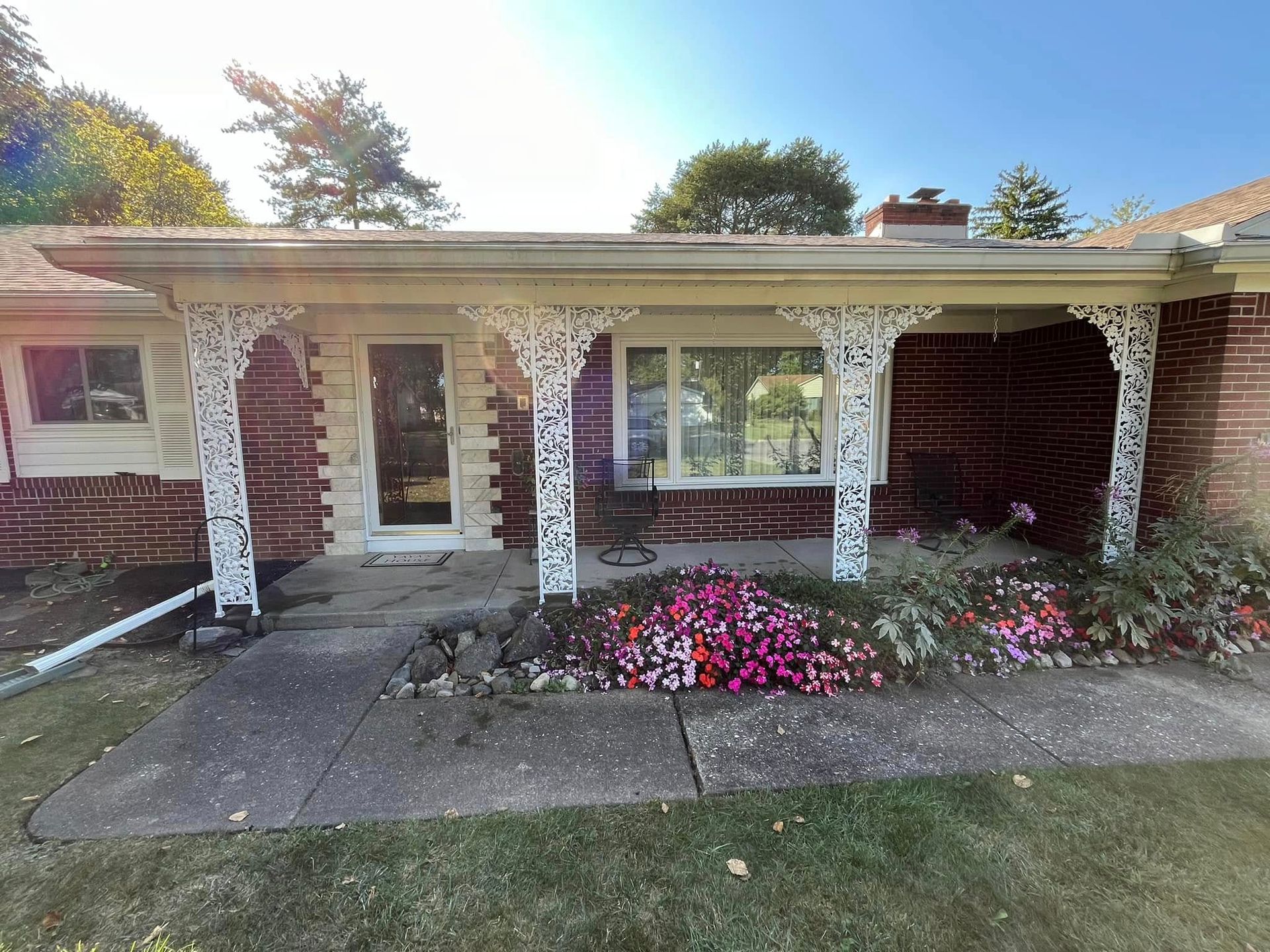 A brick house with a porch and flowers in front of it.