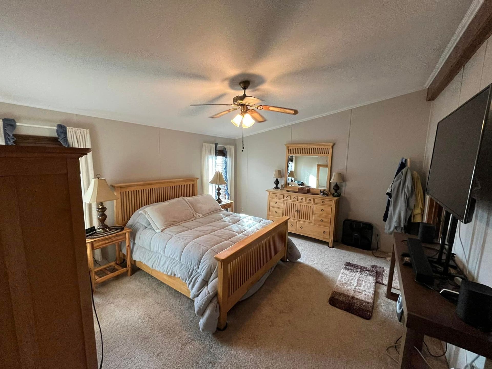 A bedroom with a bed , dresser , mirror and television.