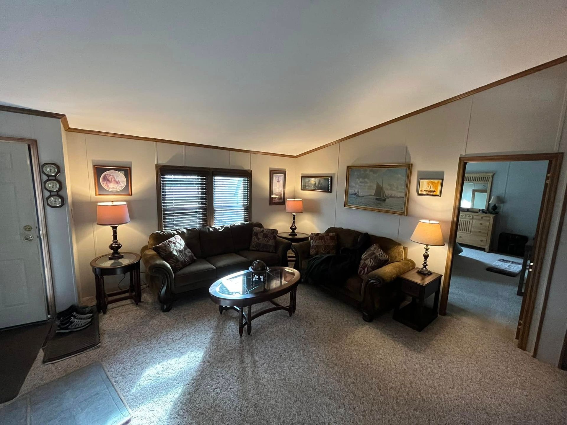 A living room with a couch , chairs , lamps , and a coffee table.
