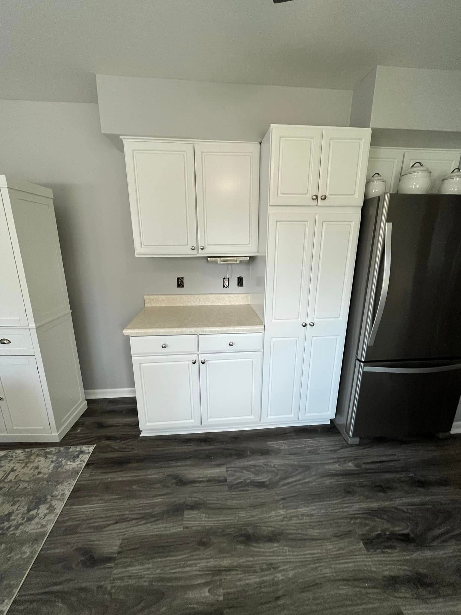A kitchen with white cabinets and a black refrigerator.