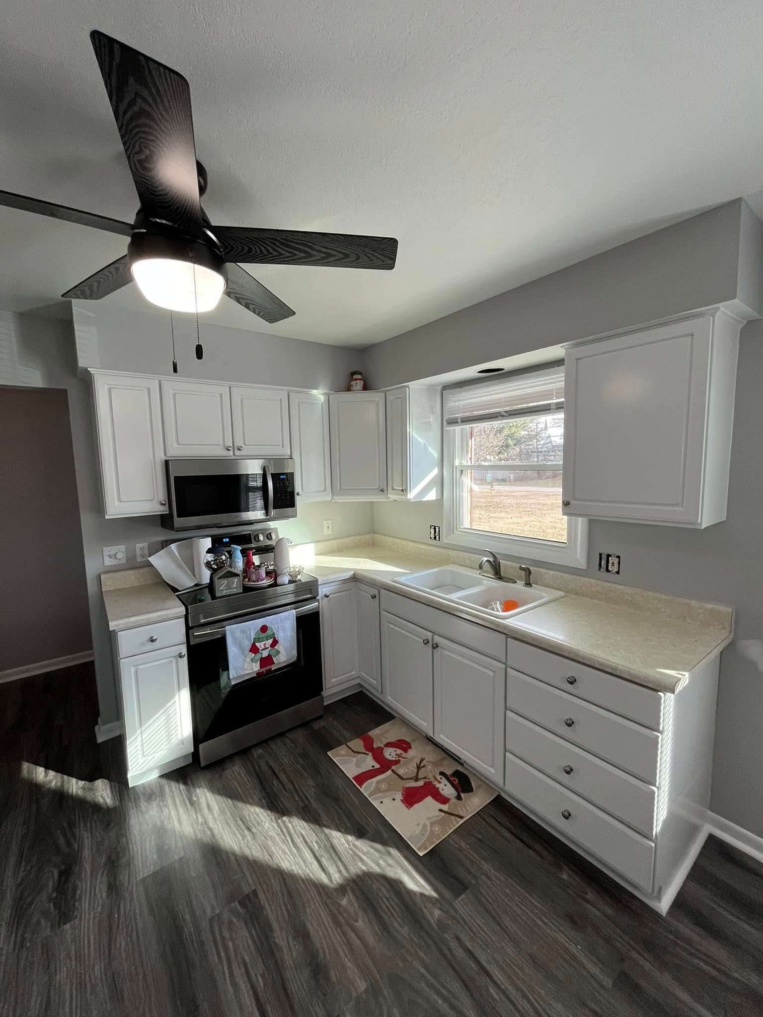 A kitchen with white cabinets and a ceiling fan.