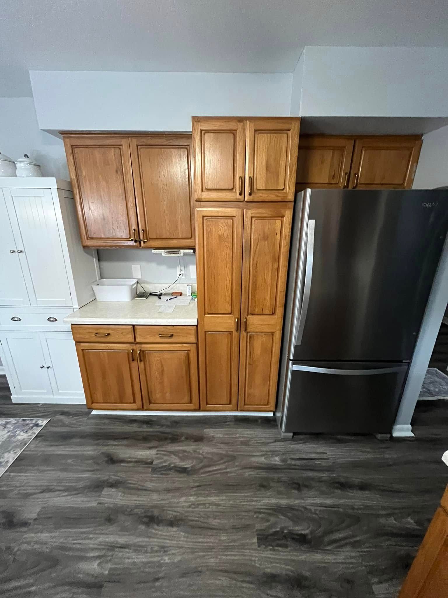 A kitchen with wooden cabinets and a stainless steel refrigerator.