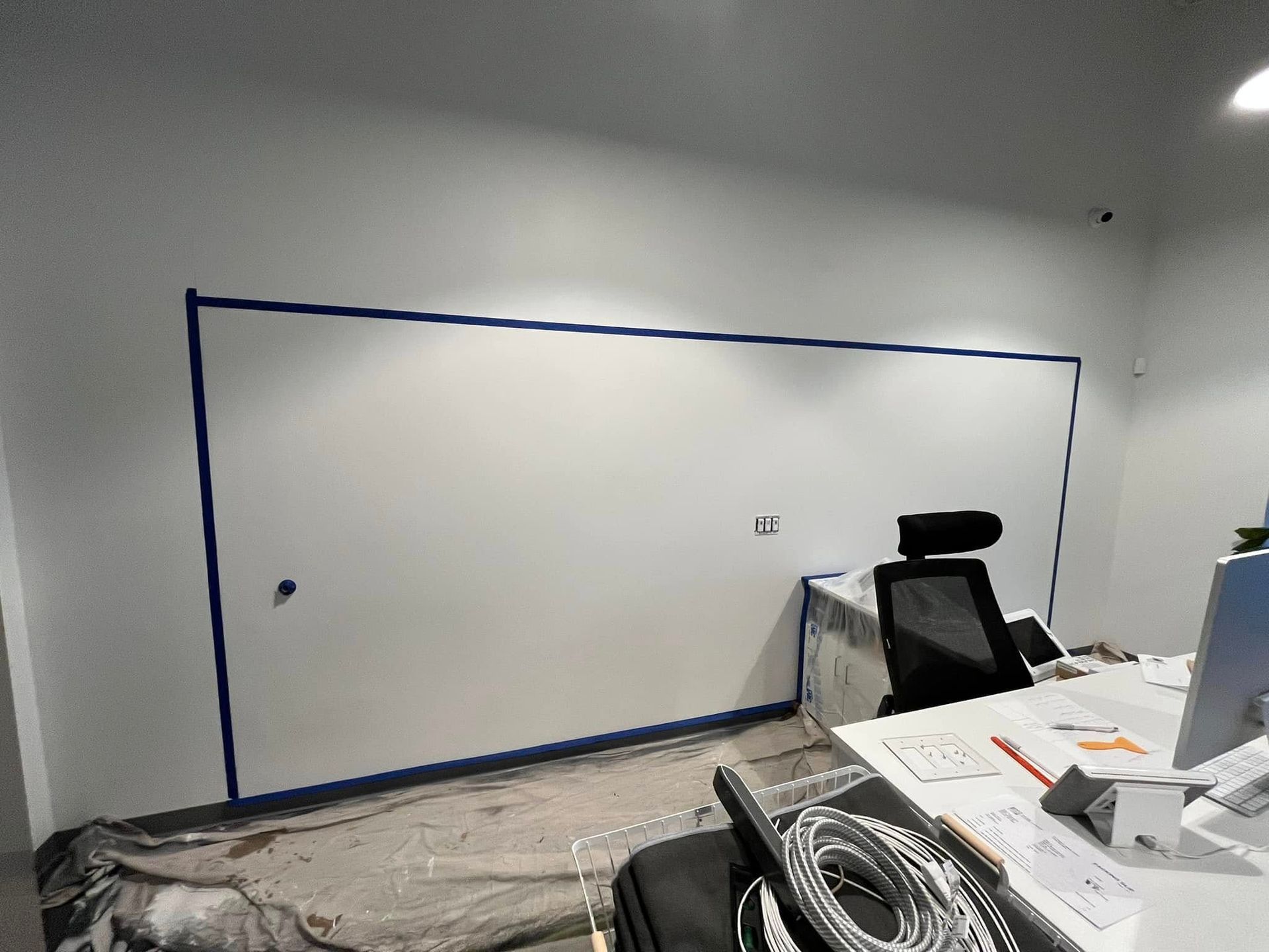 A white board is taped to the wall in an office.