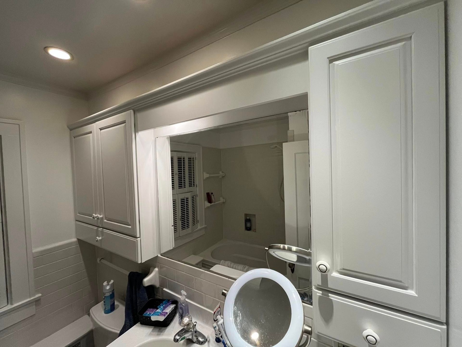 A bathroom with a sink , toilet , mirror and cabinets.
