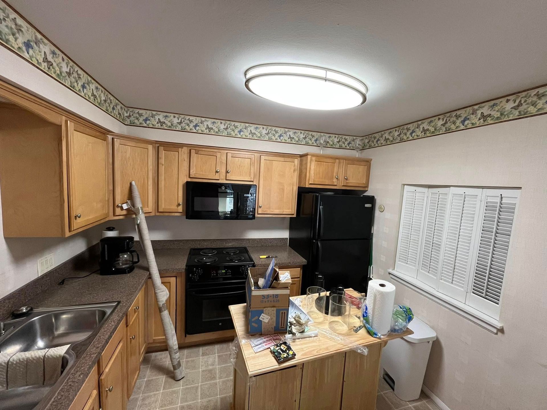 A kitchen with wooden cabinets and a black refrigerator