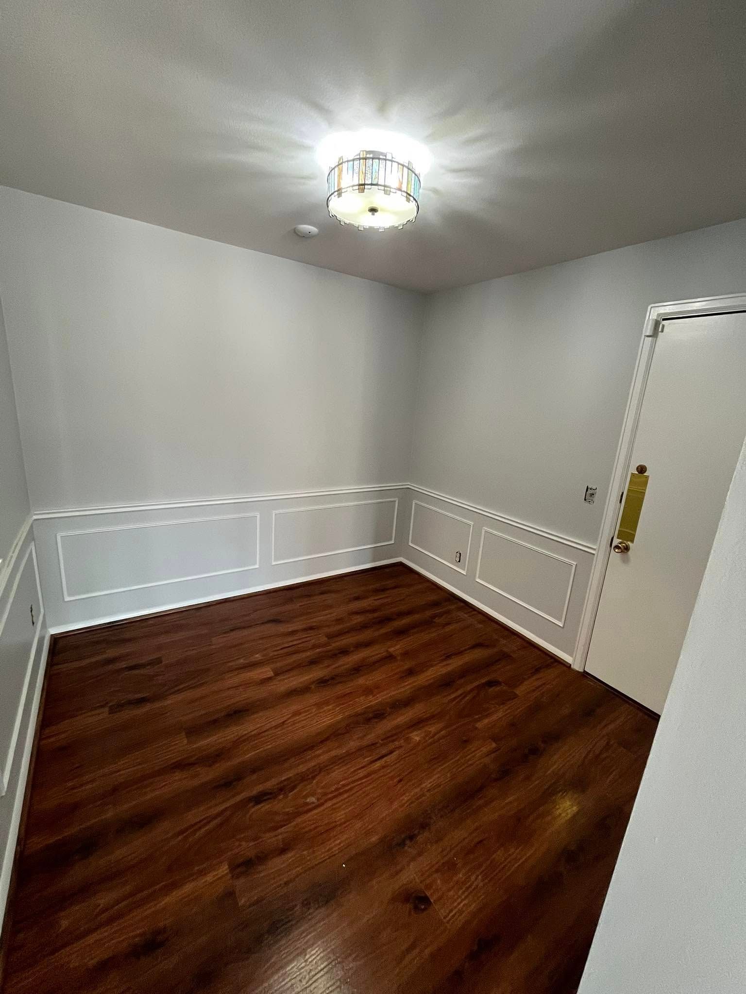 An empty room with hardwood floors and white walls.