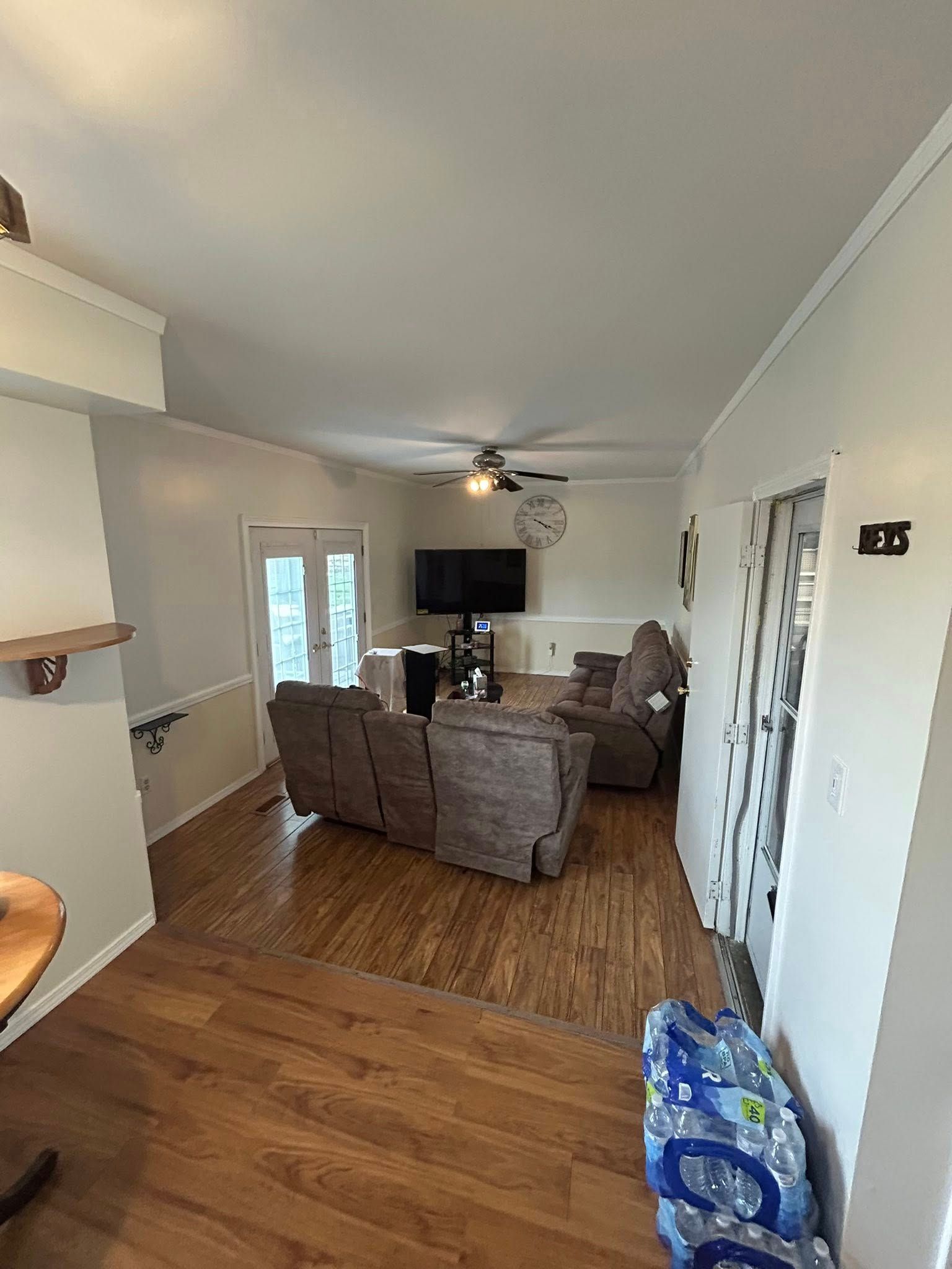 A living room with hardwood floors , a couch , chairs and a flat screen tv.