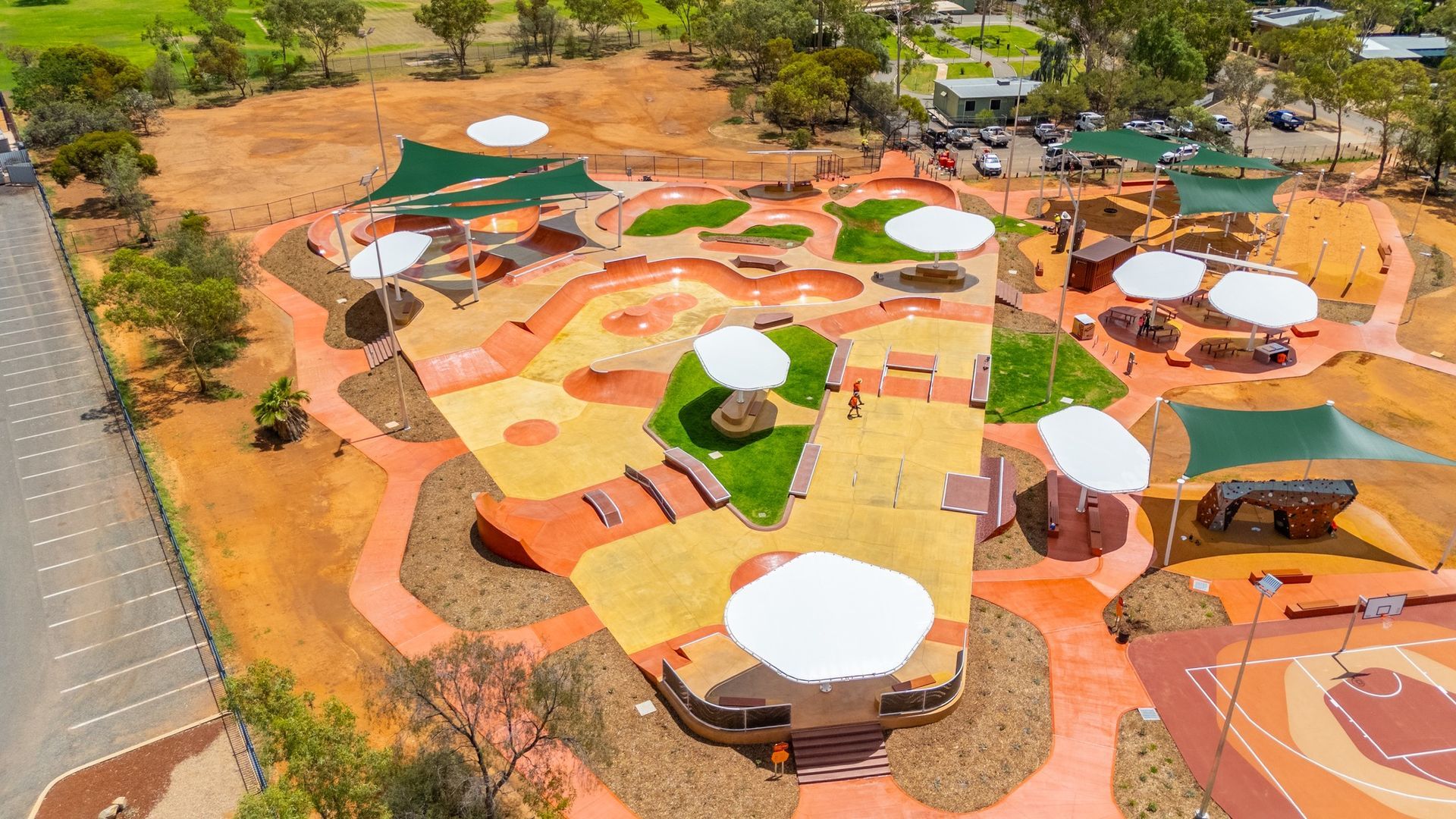 Aerial view of a colorful outdoor playground with shaded areas, paths, and various play structures.