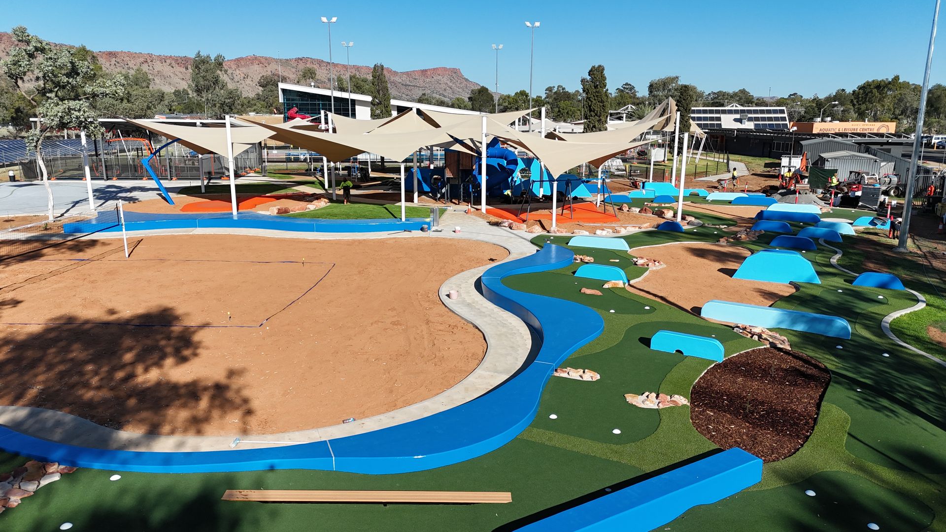 Playground with water features, shade structures, and various play areas; outdoor, sunny.