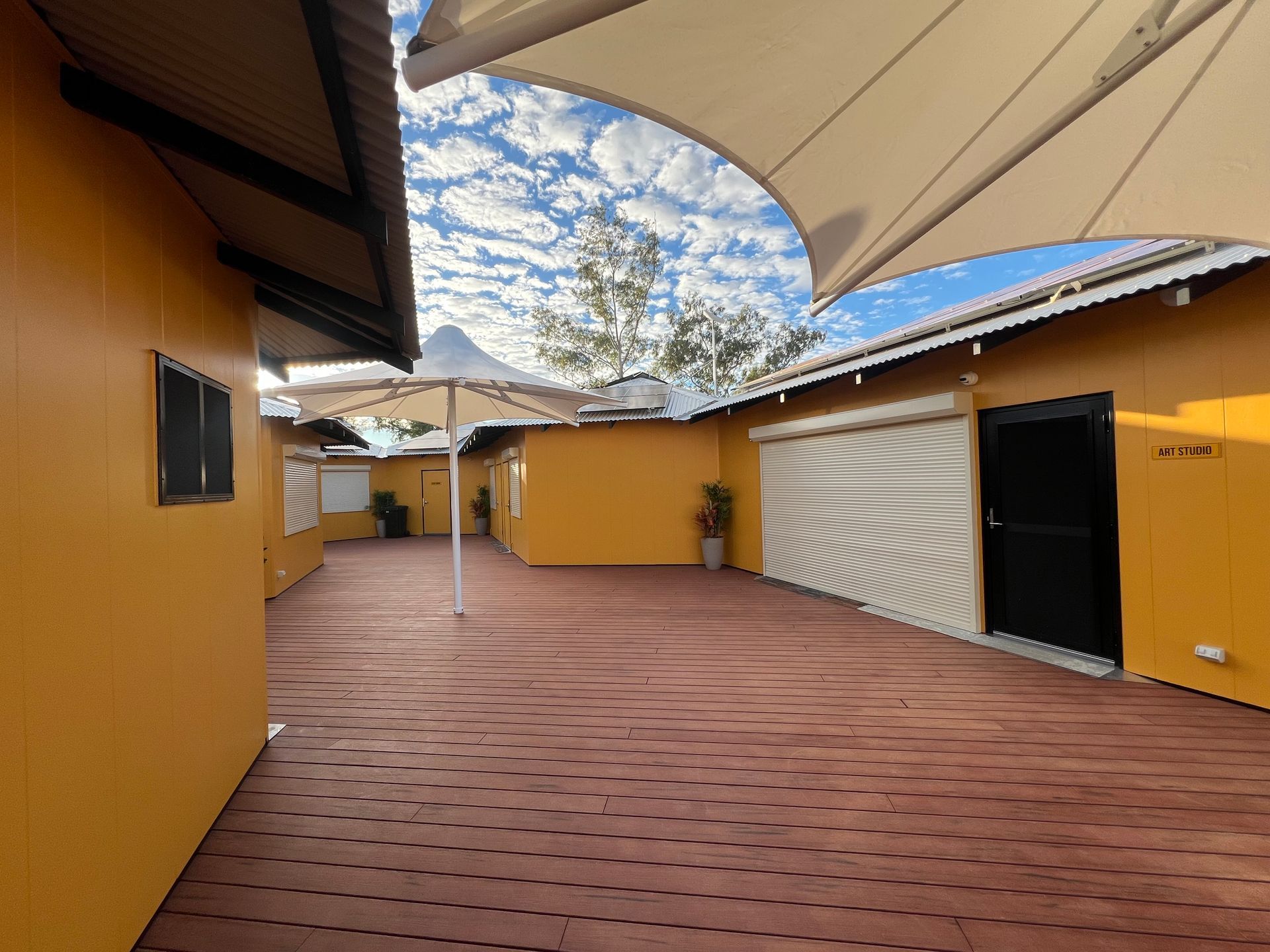 Yellow buildings with brown deck and white canopy, blue sky.
