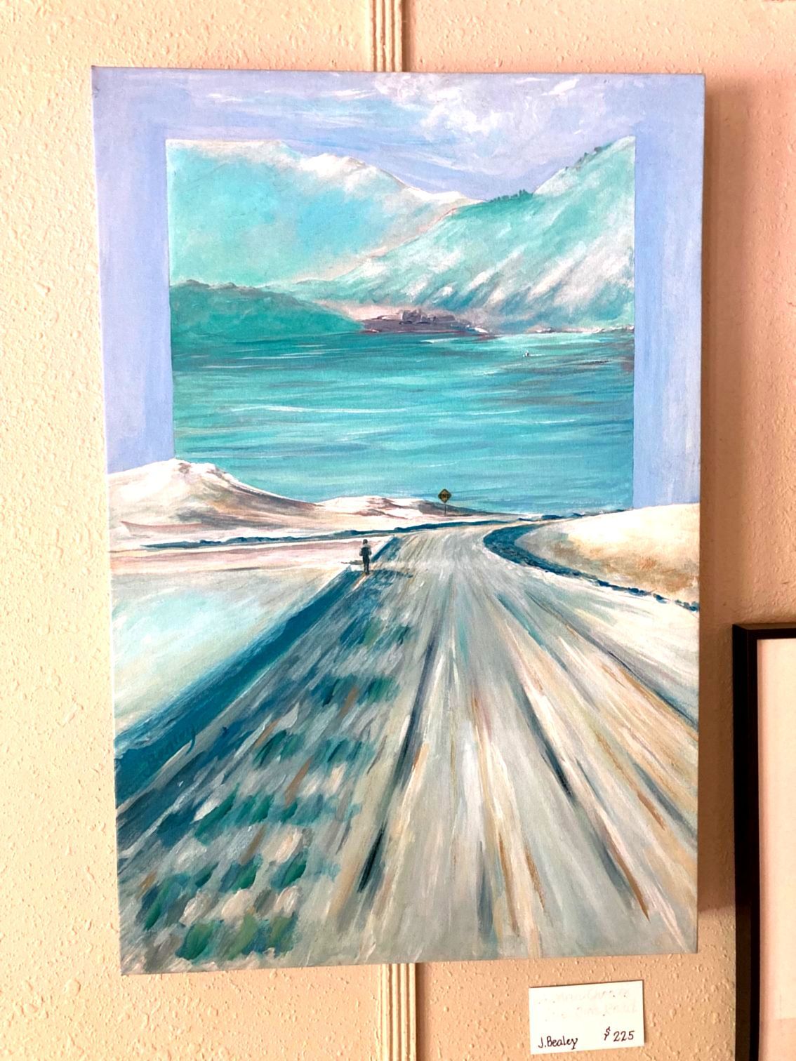 A painting of a snowy road with mountains in the background is hanging on a wall.