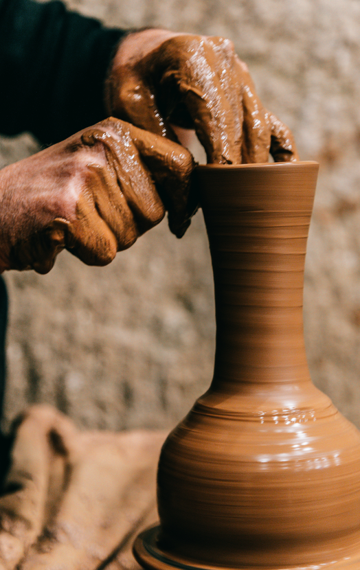 A person is making a vase out of clay on a pottery wheel