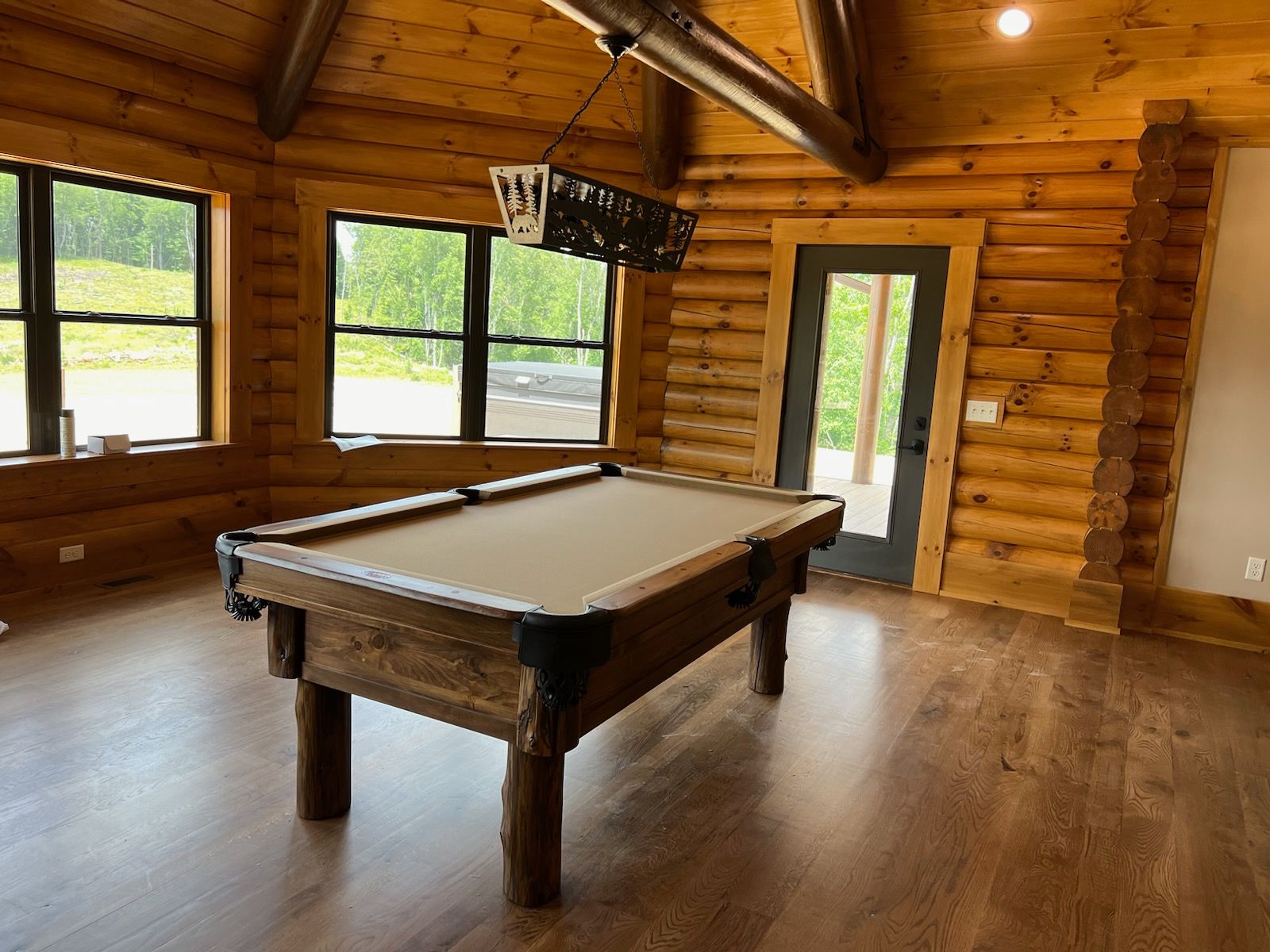 A pool table is sitting in a room in a log cabin.