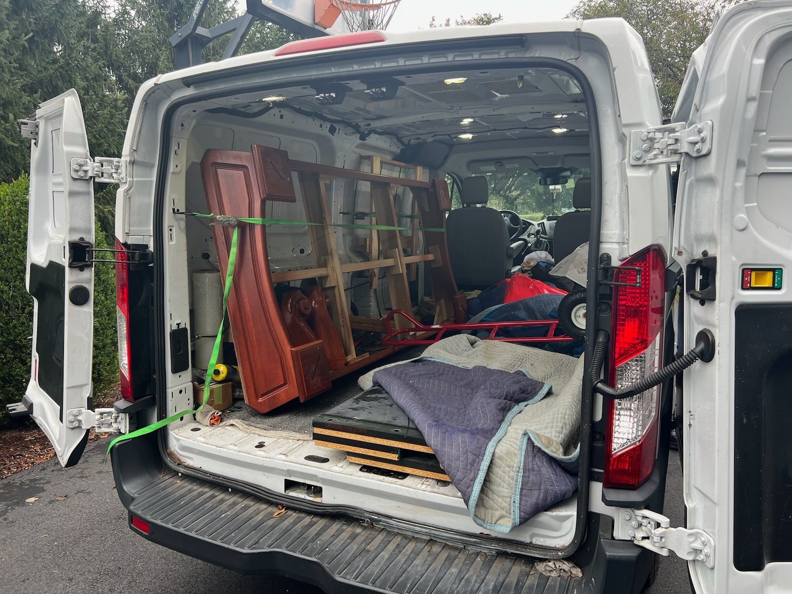 The back of a white van is filled with furniture.