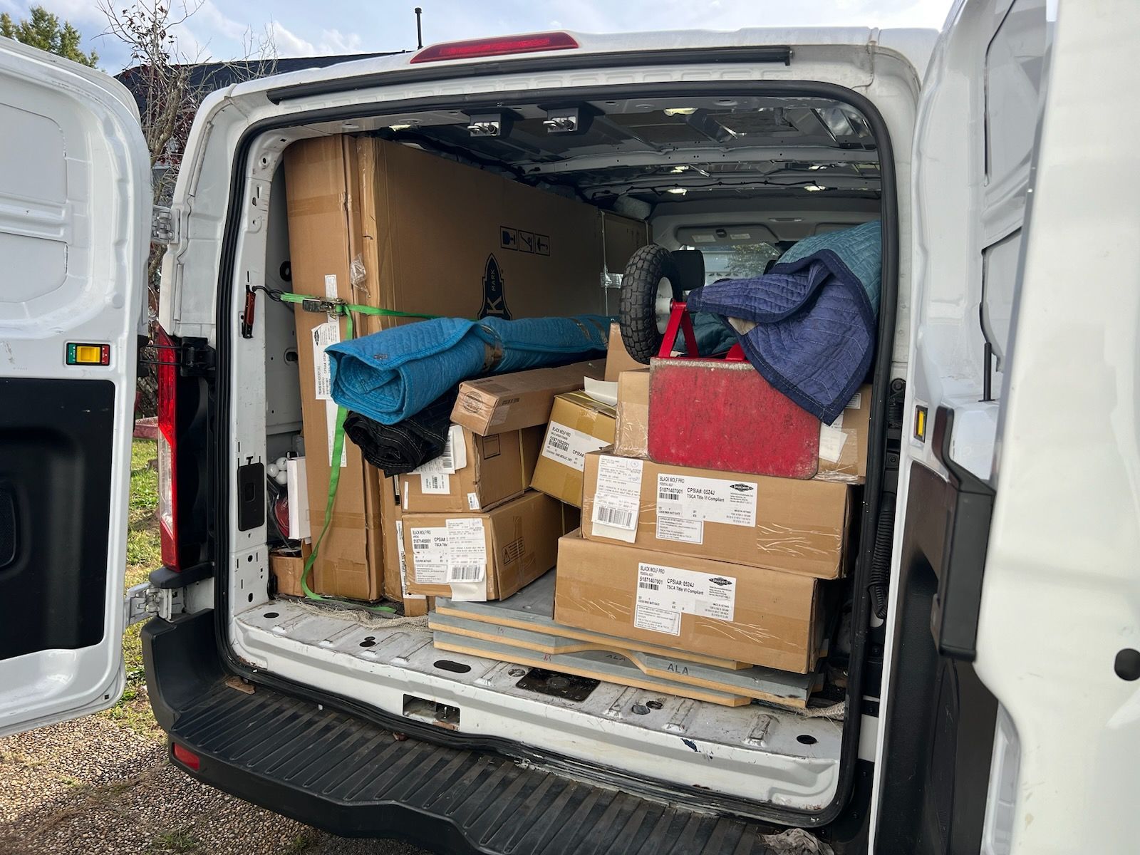 The back of a white van is filled with boxes and a bike.