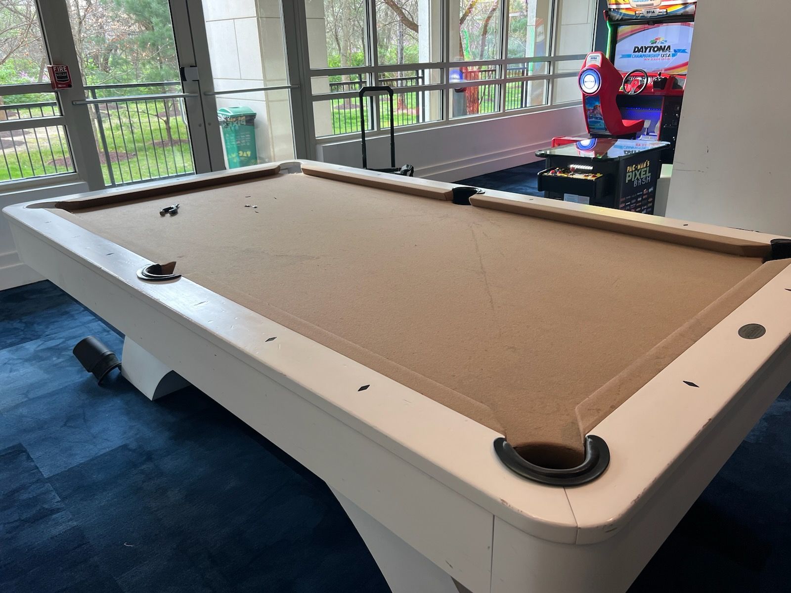 A pool table is sitting in front of a window in a room.
