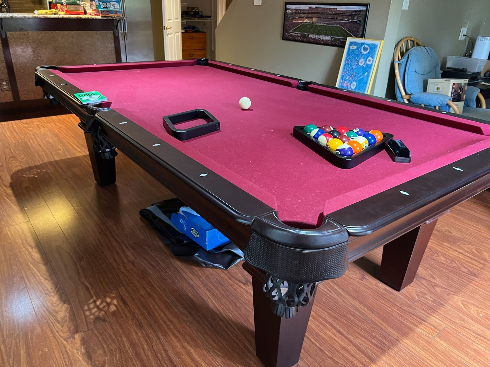 A pool table is sitting on a wooden floor in a living room.