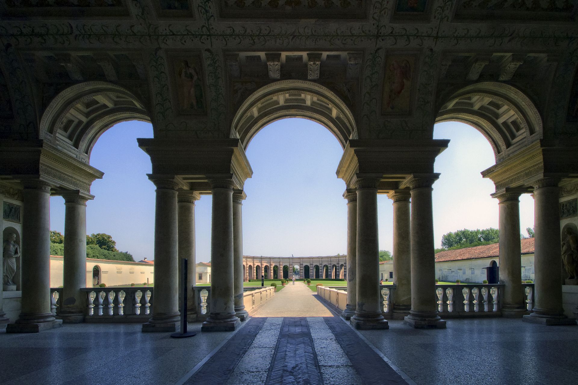 A building with columns and arches looking out to a field