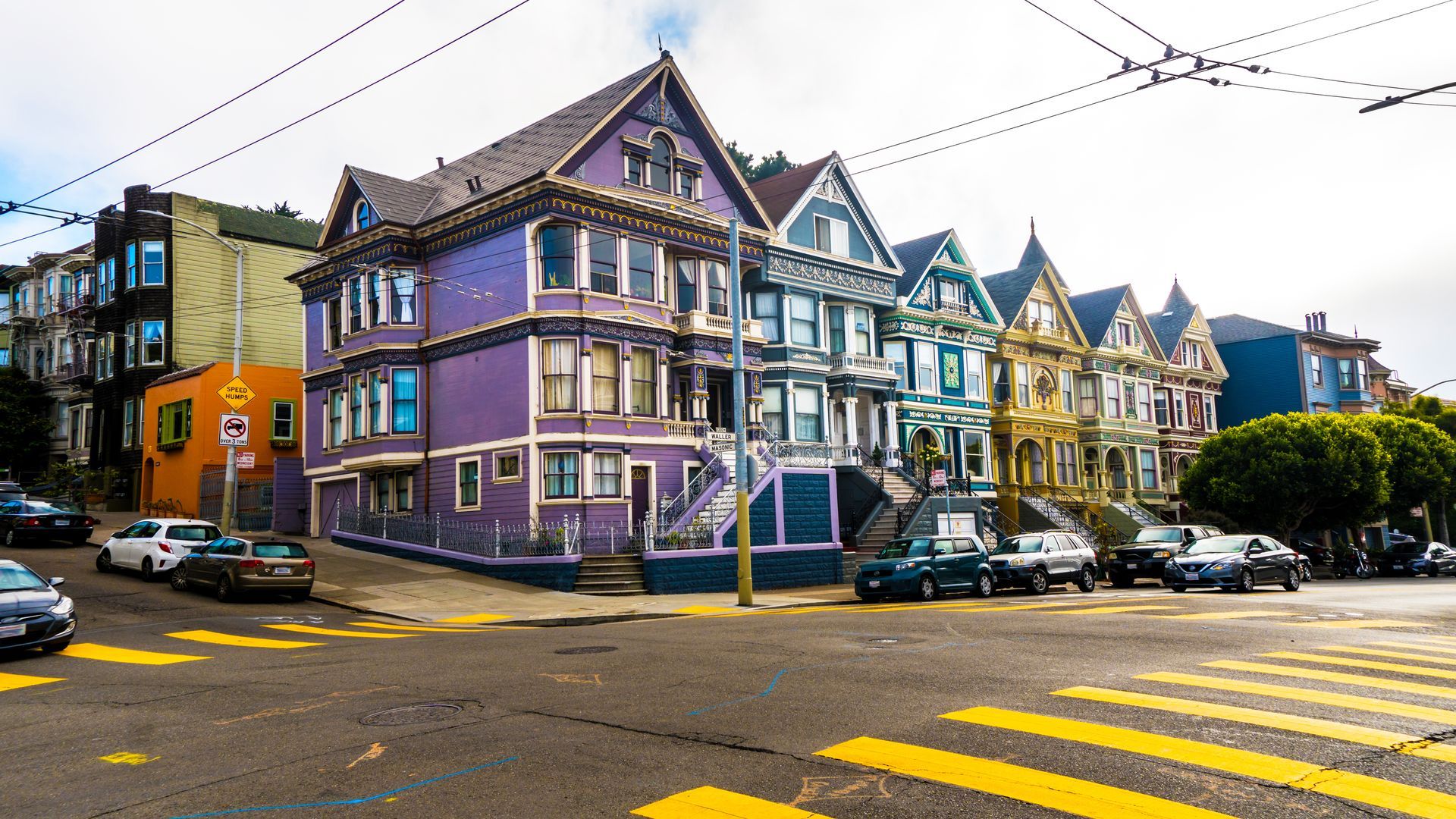 A row of colorful houses are lined up on the corner of a street.