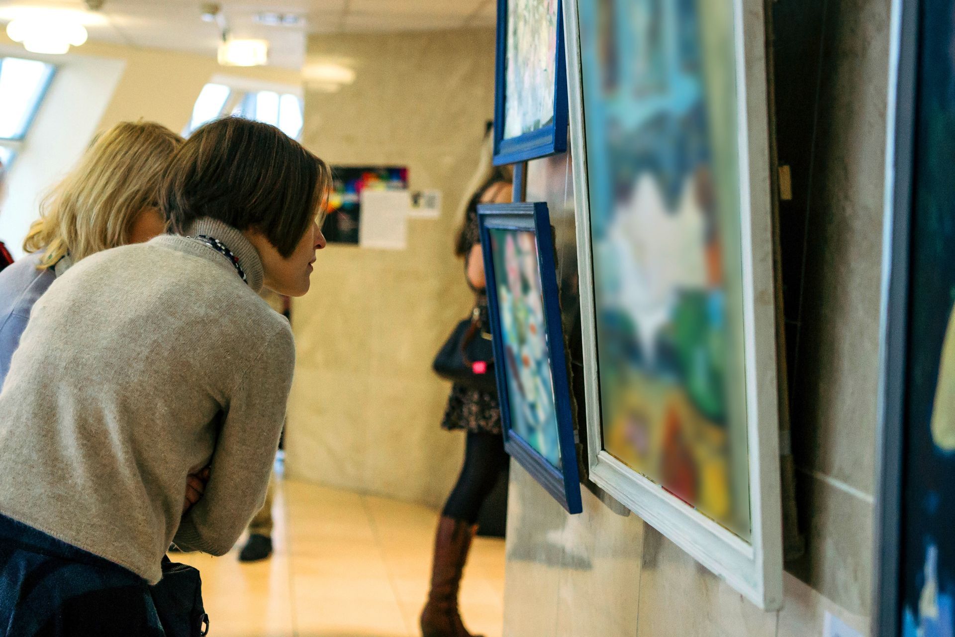 Two women are looking at paintings on a wall in a museum.