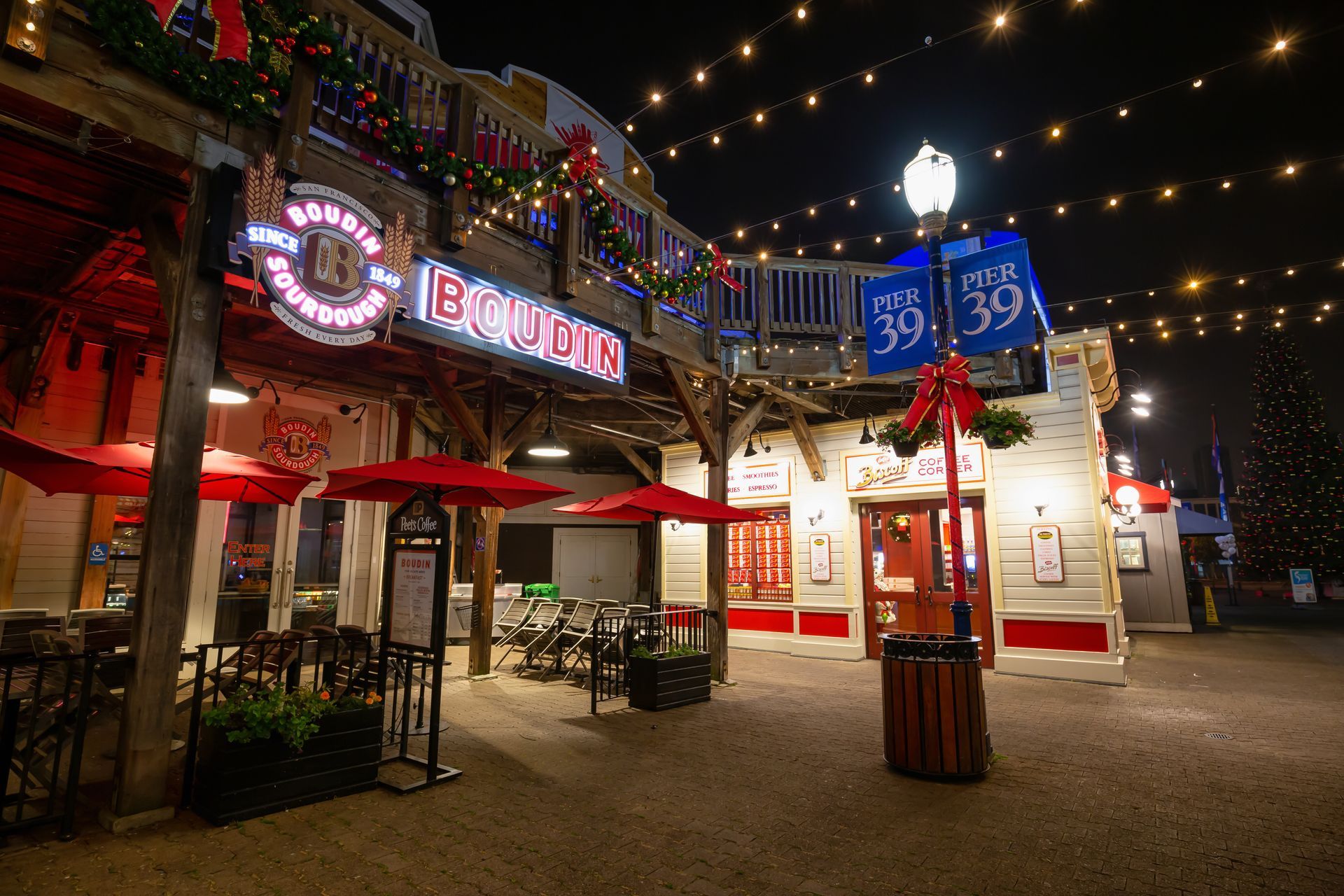 A restaurant with red umbrellas is lit up at night.
