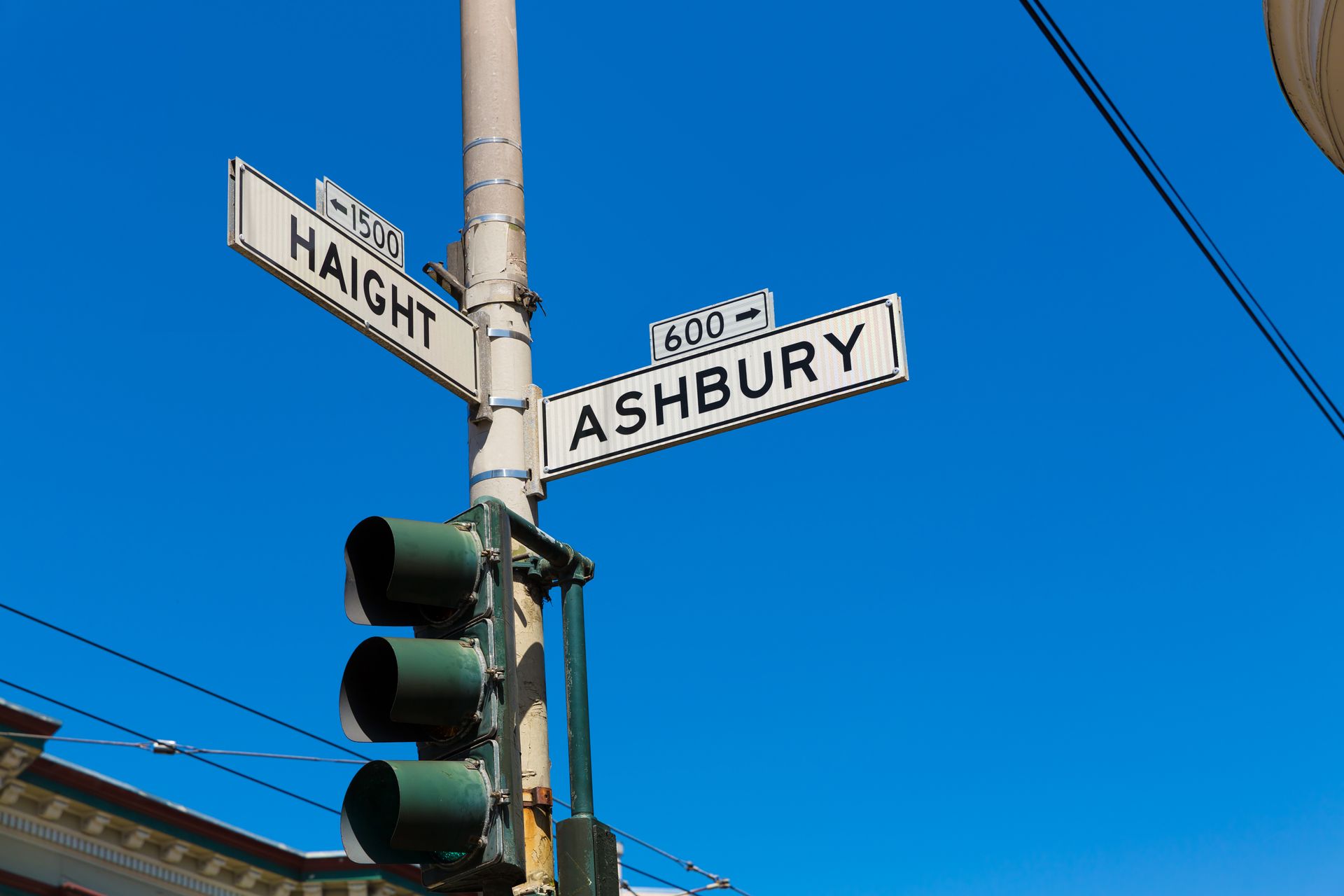 A street sign for ashbury is hanging on a pole next to a traffic light.