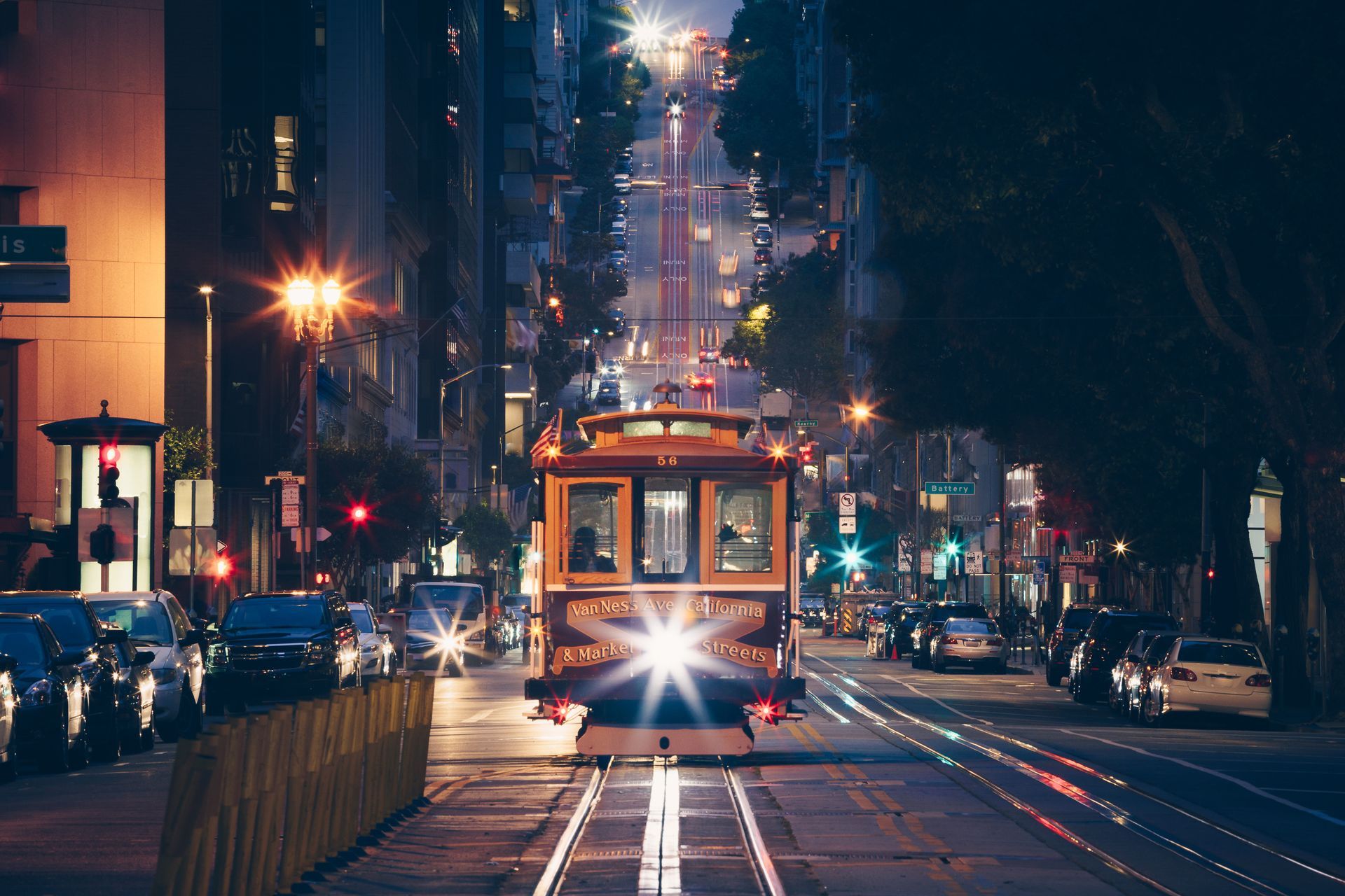 A trolley is driving down a city street at night.