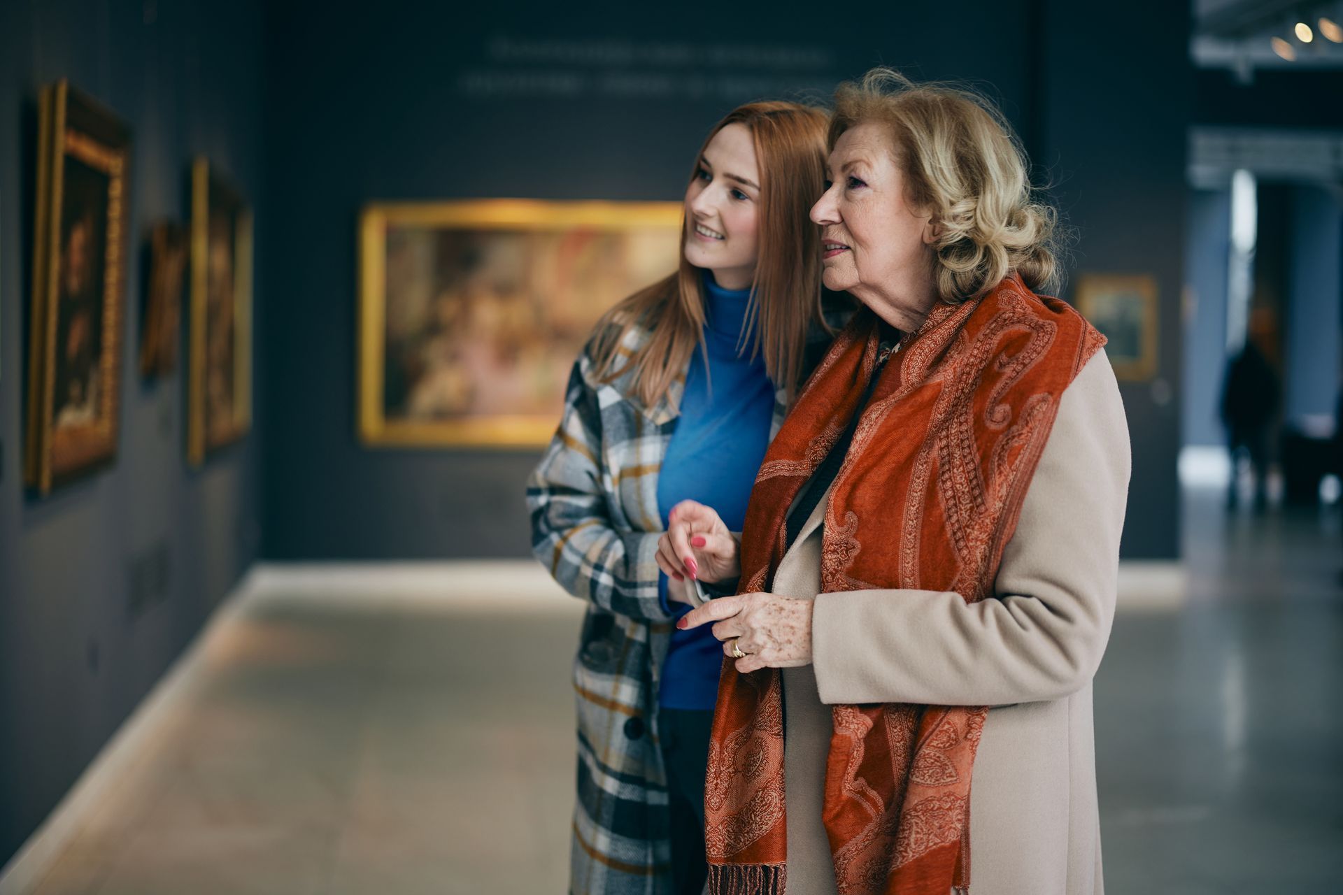 Two women are looking at paintings in a museum.