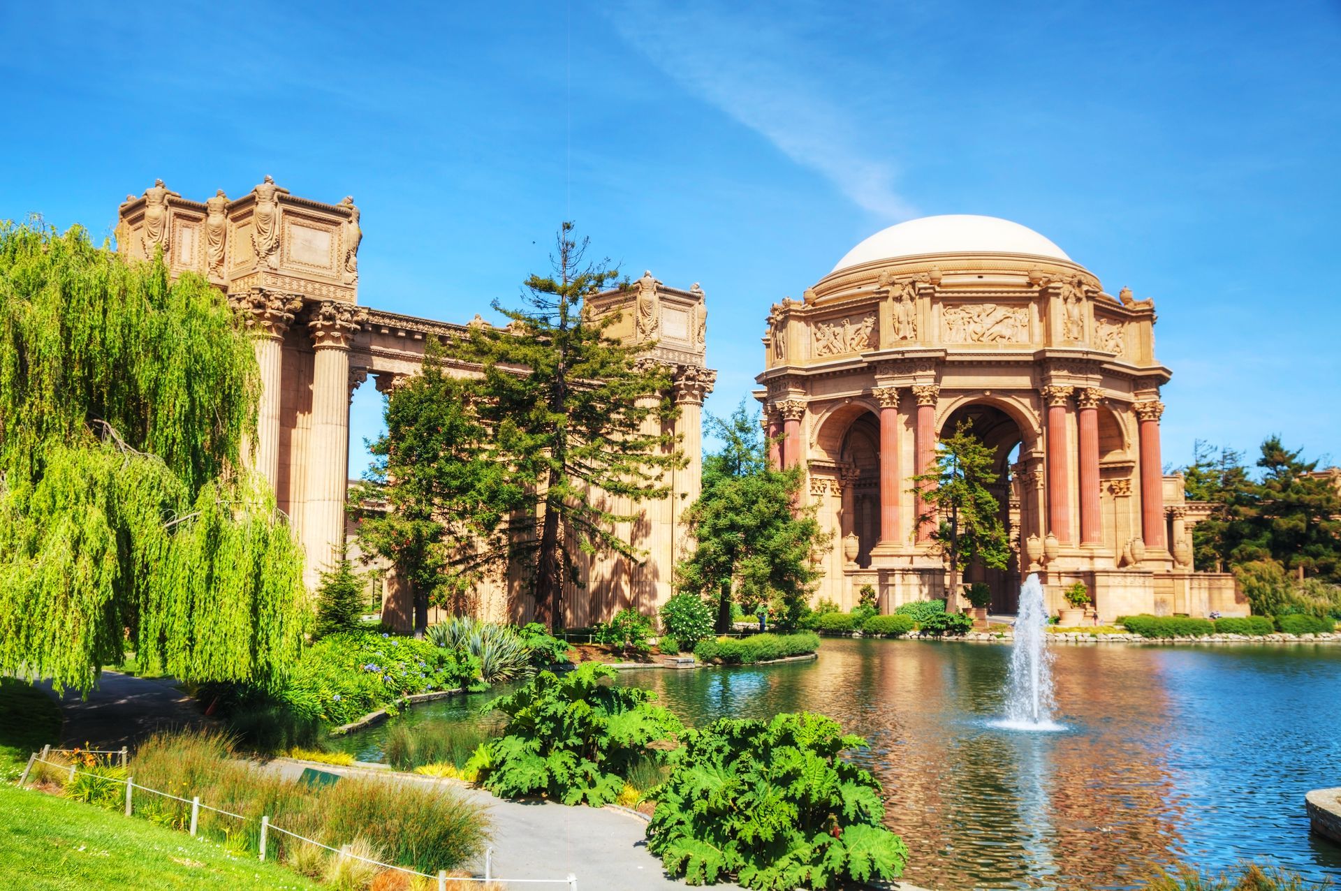 A large building with a fountain in front of it in a park.
