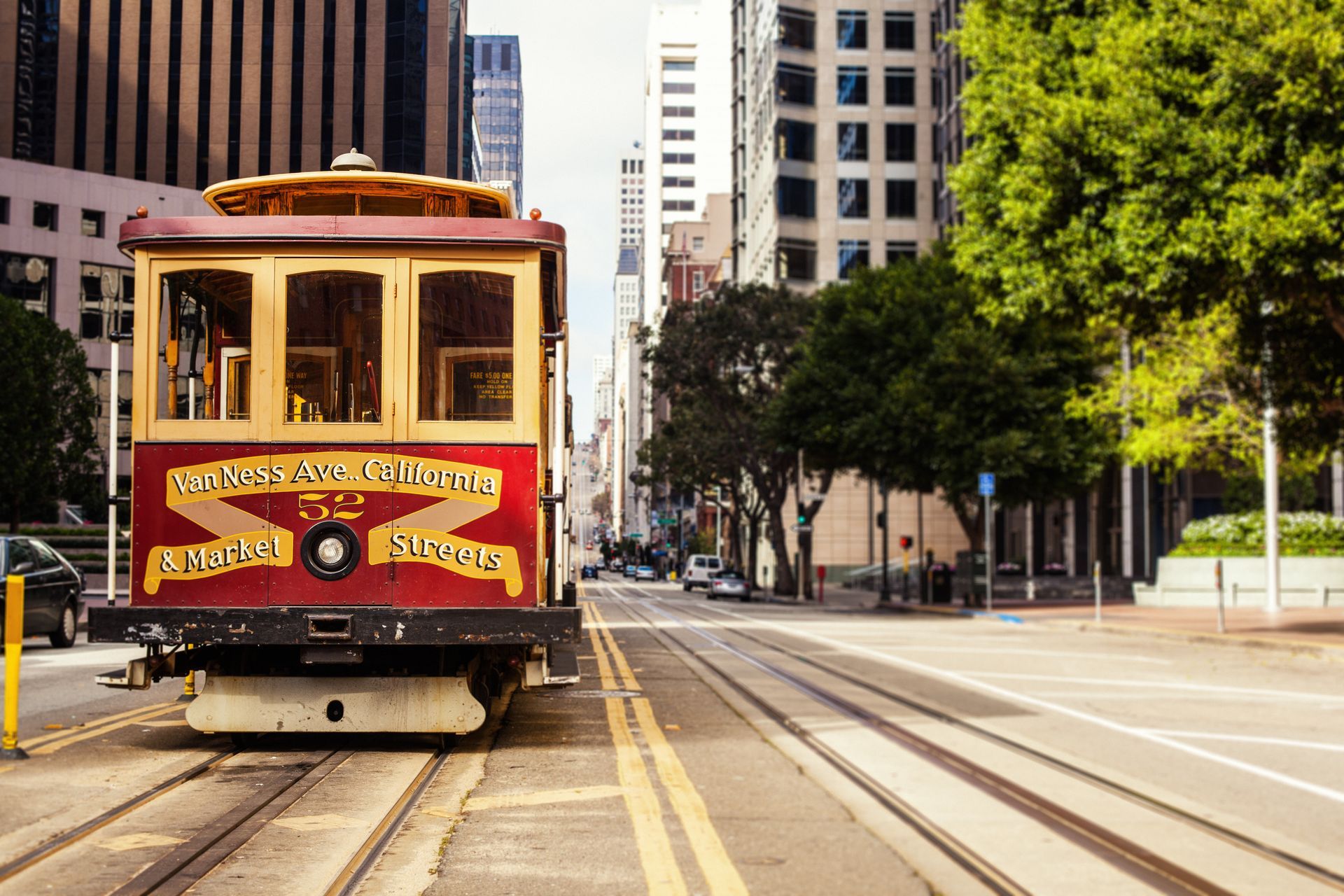 A red and yellow trolley is driving down a city street.
