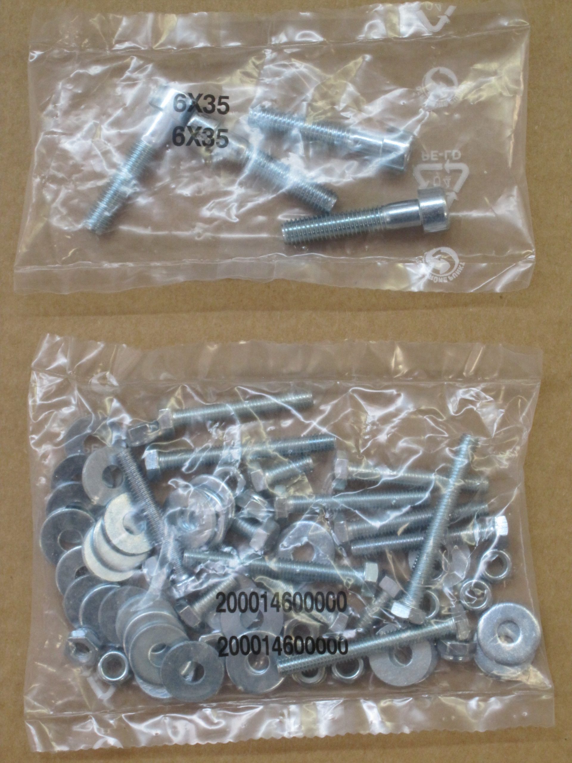 Due sacchetti di plastica trasparente contenenti bulloni, rondelle e dadi su uno sfondo neutro.