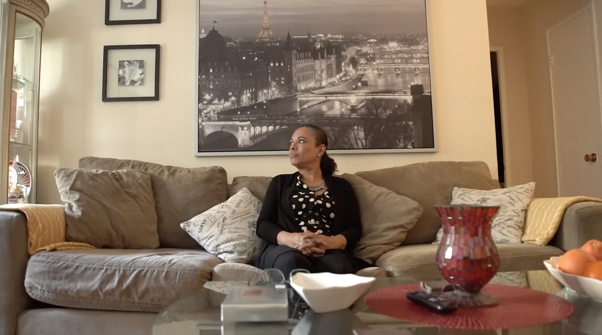 A woman is sitting on a couch in a living room.