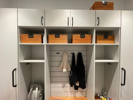 A room with white cabinets and wicker baskets on the shelves