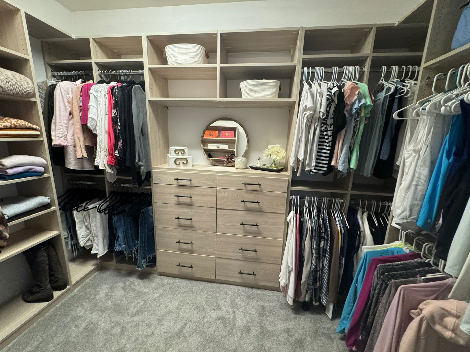 A walk in closet filled with lots of clothes and a mirror.