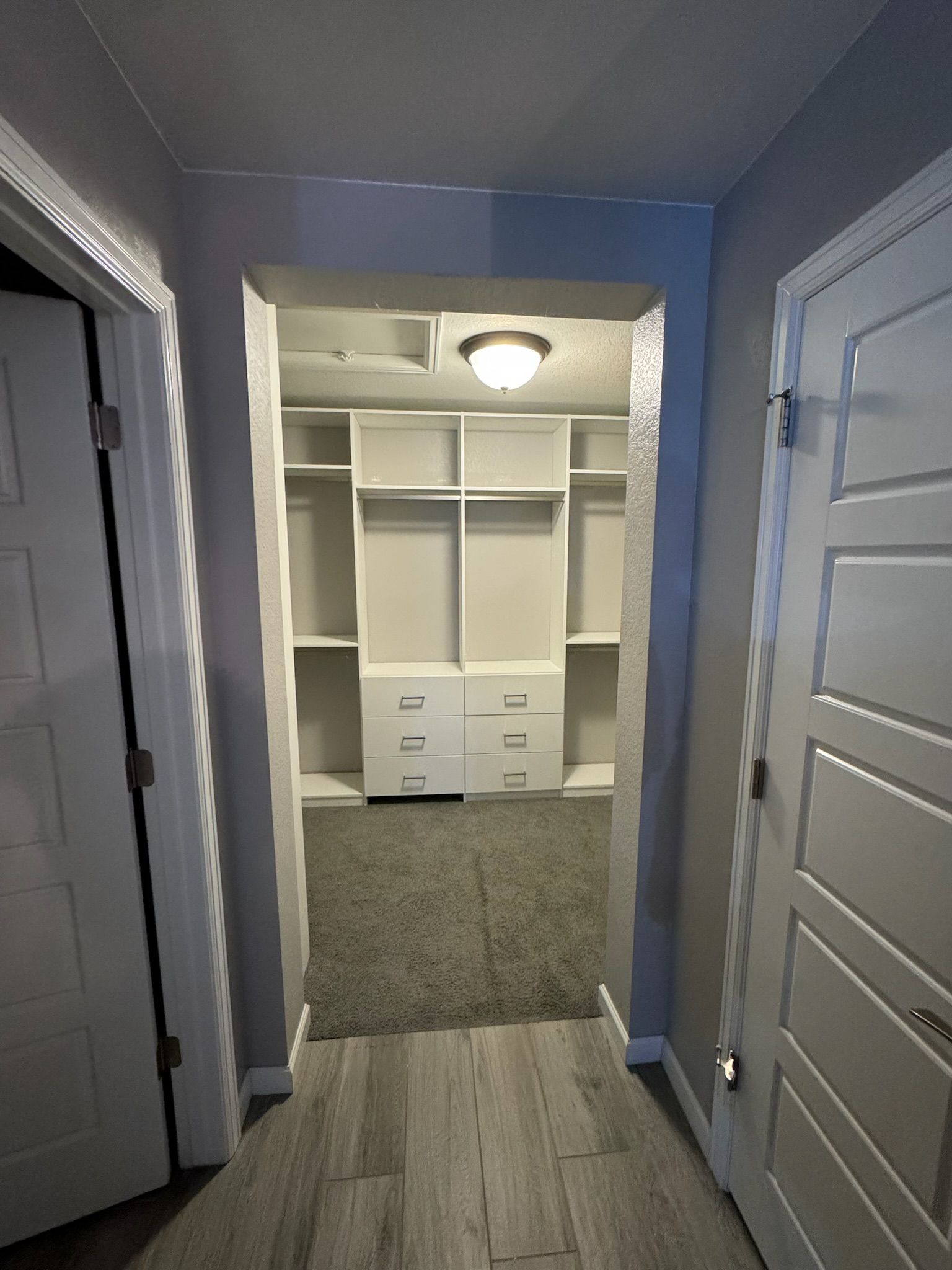 A hallway leading to a walk in closet in a house.